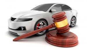 Carro prata atrás de um martelo de leiloeiro, representando leilão de veículos